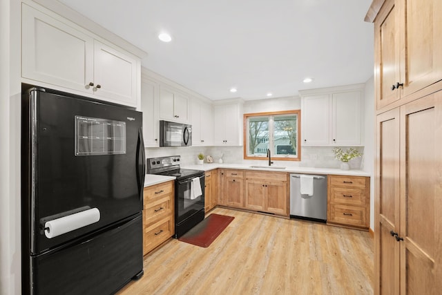 kitchen featuring sink, backsplash, white cabinets, light hardwood / wood-style floors, and black appliances