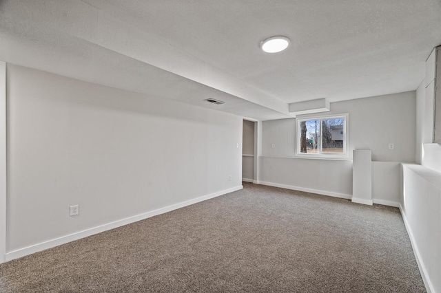 below grade area featuring visible vents, carpet flooring, a textured ceiling, and baseboards