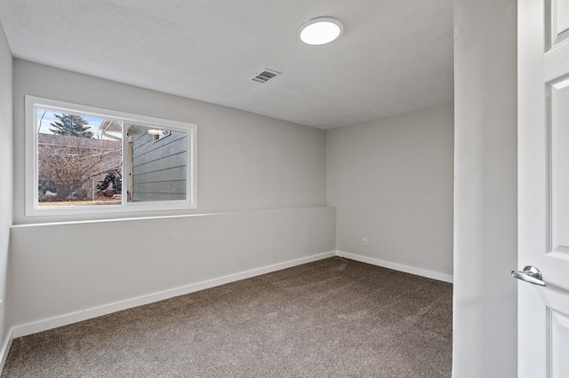 spare room with visible vents, baseboards, and dark colored carpet