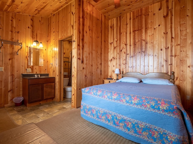 bedroom with wood ceiling, ensuite bath, and wood walls