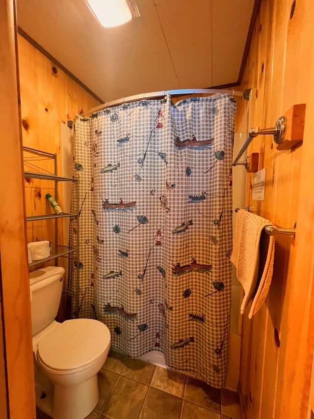 bathroom featuring tile patterned floors, a shower with shower curtain, toilet, and wood walls