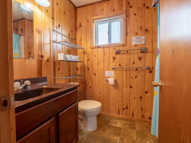 bathroom with vanity, wooden walls, tile patterned floors, and toilet