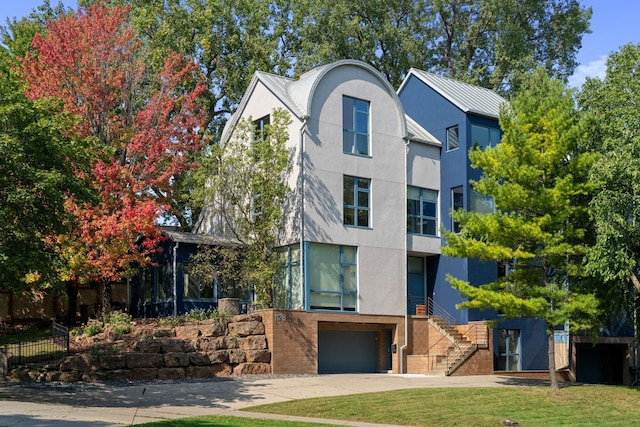 view of front of home with driveway, a standing seam roof, metal roof, and stucco siding