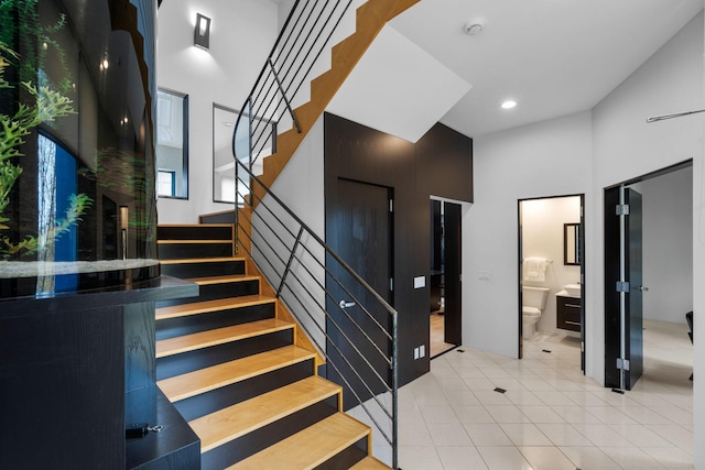 stairs featuring a towering ceiling, tile patterned flooring, and recessed lighting