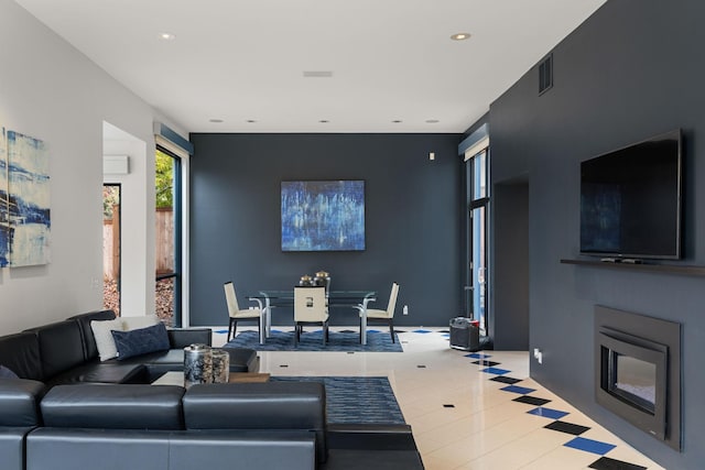 tiled living area featuring recessed lighting, visible vents, baseboards, and a glass covered fireplace