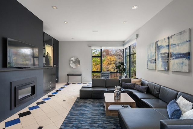 living area with recessed lighting, light tile patterned flooring, and a glass covered fireplace