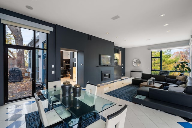 dining space featuring light tile patterned floors, a glass covered fireplace, visible vents, and recessed lighting