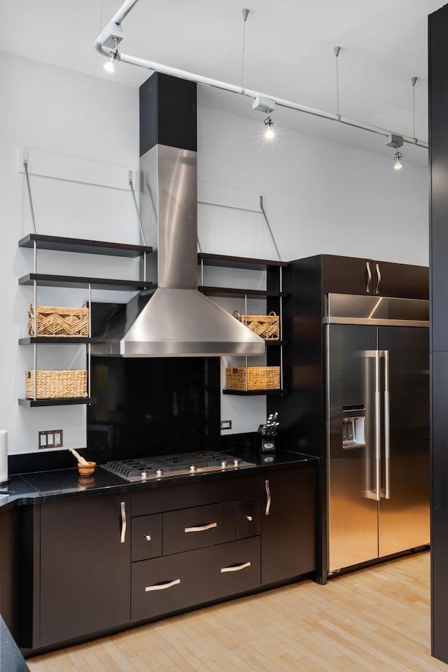 kitchen with stainless steel appliances, dark countertops, island range hood, and open shelves