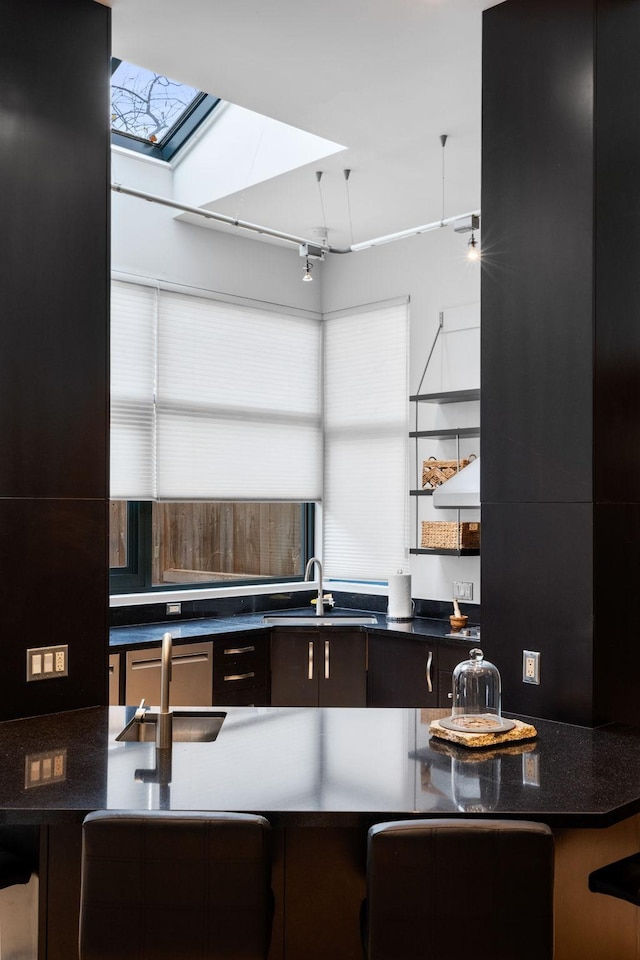 kitchen with a healthy amount of sunlight, dark countertops, track lighting, and a sink