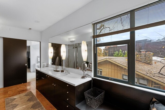 bathroom with double vanity, an enclosed shower, and a sink