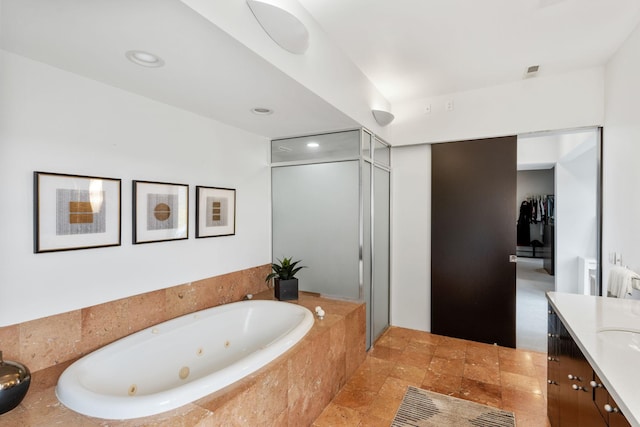 bathroom featuring a stall shower, vanity, a tub with jets, and recessed lighting