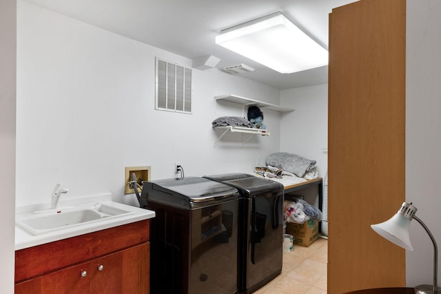 washroom with light tile patterned flooring, visible vents, a sink, and independent washer and dryer