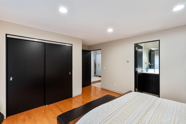 bedroom with ensuite bath, light wood-style flooring, a sink, a closet, and recessed lighting