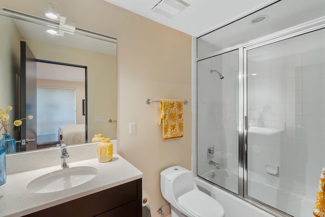 full bathroom with toilet, bath / shower combo with glass door, vanity, visible vents, and ensuite bath