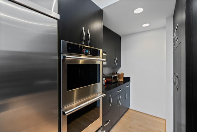 1128 Kenwood Pkwy, Minneapolis, MN 55403 - kitchen featuring dark countertops, light wood-type flooring, recessed lighting, stainless steel appliances, and dark cabinets