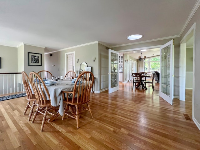 dining room featuring french doors, ornamental molding, a chandelier, and hardwood / wood-style floors