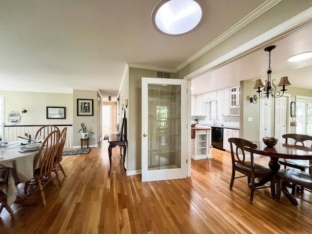 dining space featuring ornamental molding, a chandelier, and light hardwood / wood-style flooring