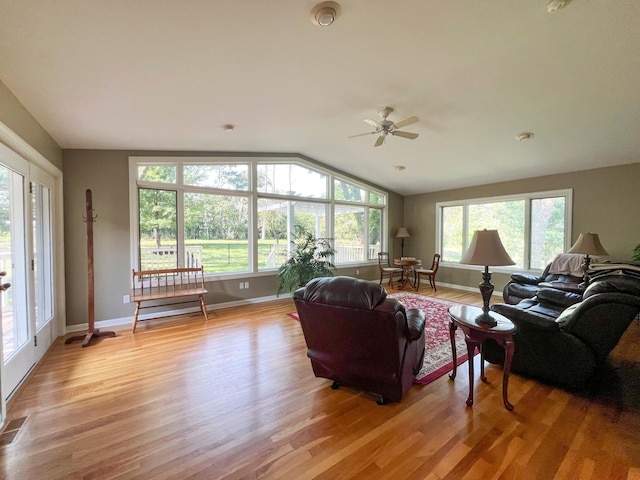 living room with ceiling fan, vaulted ceiling, and light hardwood / wood-style flooring