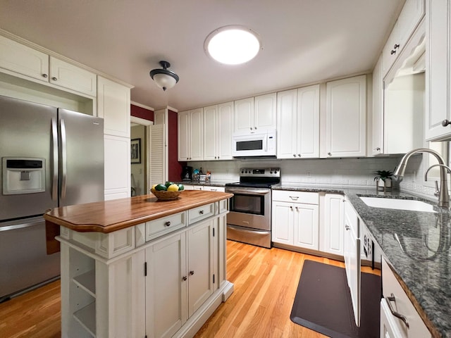 kitchen featuring appliances with stainless steel finishes, sink, white cabinets, a center island, and light hardwood / wood-style floors