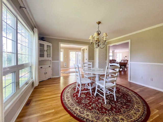 dining room with an inviting chandelier, light hardwood / wood-style flooring, and ornamental molding