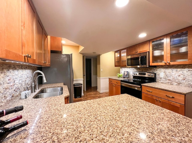 kitchen featuring appliances with stainless steel finishes, sink, backsplash, and light stone counters