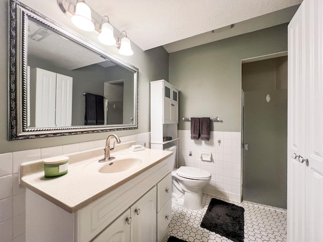 bathroom featuring tile walls, tile patterned flooring, vanity, an enclosed shower, and toilet