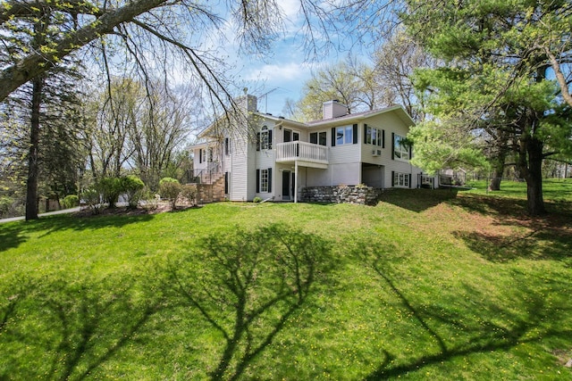 rear view of property with a balcony and a lawn