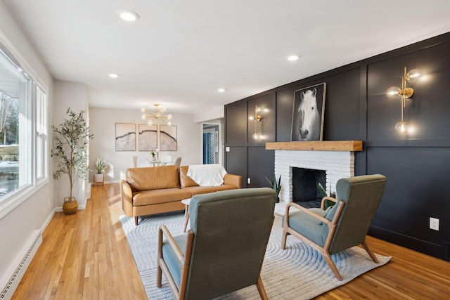 living room featuring baseboard heating, a fireplace, and light wood-type flooring