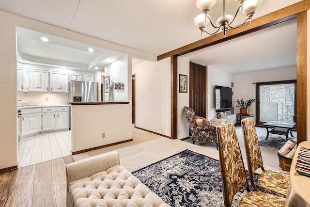 dining room featuring an inviting chandelier, light hardwood / wood-style floors, and beamed ceiling