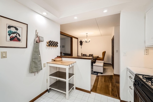 kitchen featuring white cabinetry, an inviting chandelier, light tile patterned floors, black gas stove, and pendant lighting