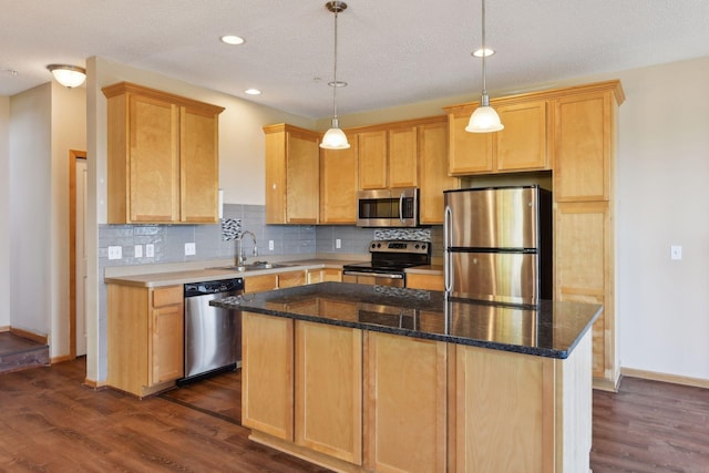 kitchen with sink, a center island, hanging light fixtures, appliances with stainless steel finishes, and dark stone counters