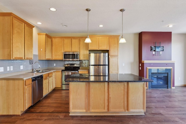 kitchen with appliances with stainless steel finishes, a center island, sink, and hanging light fixtures