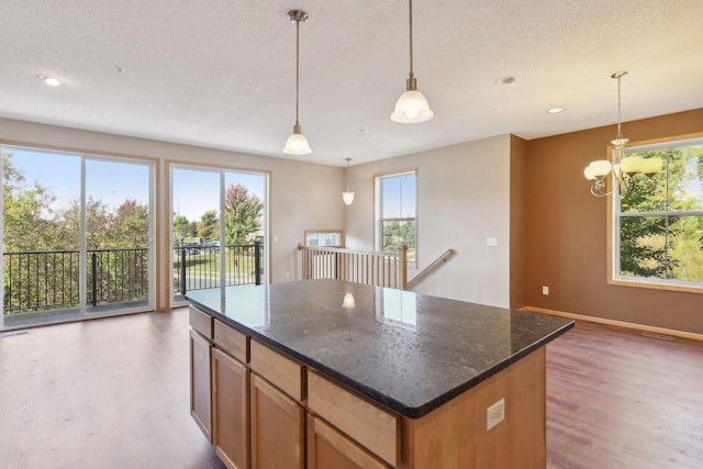 kitchen featuring wood-type flooring, a textured ceiling, hanging light fixtures, and dark stone countertops