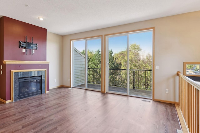 unfurnished living room with a tiled fireplace, hardwood / wood-style flooring, and a textured ceiling