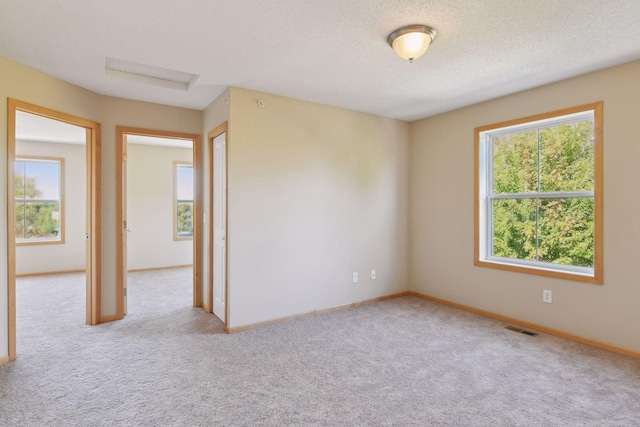 spare room with light carpet and a textured ceiling