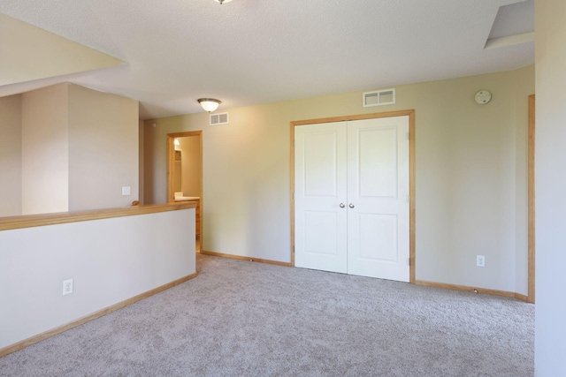 unfurnished bedroom with light carpet, a closet, and a textured ceiling