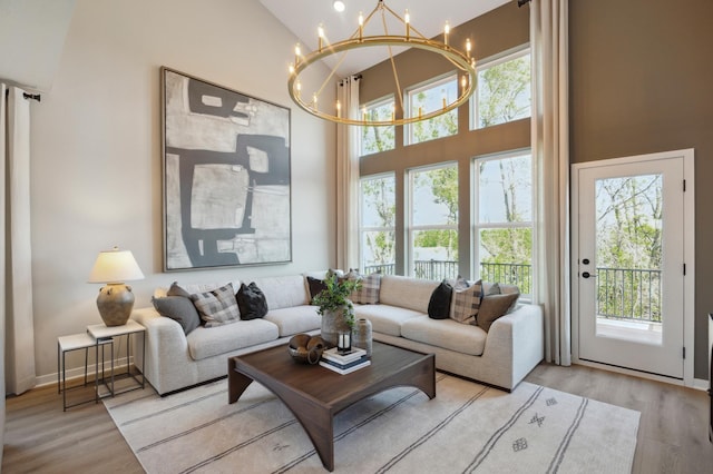 living room with an inviting chandelier, a high ceiling, and light wood-type flooring