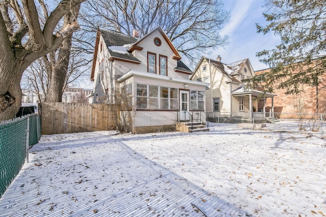 snow covered house featuring a sunroom