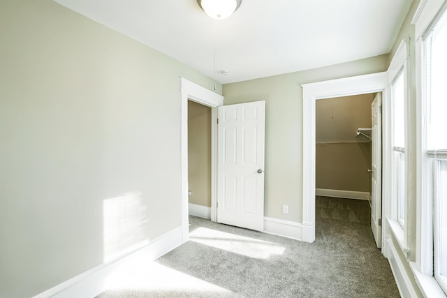 unfurnished bedroom with a spacious closet, light carpet, and a closet