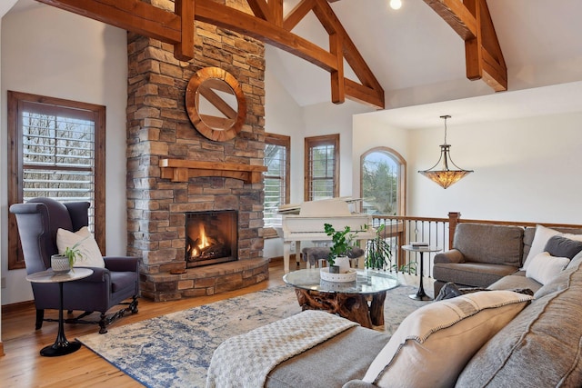 living room featuring hardwood / wood-style flooring, a stone fireplace, high vaulted ceiling, and a healthy amount of sunlight