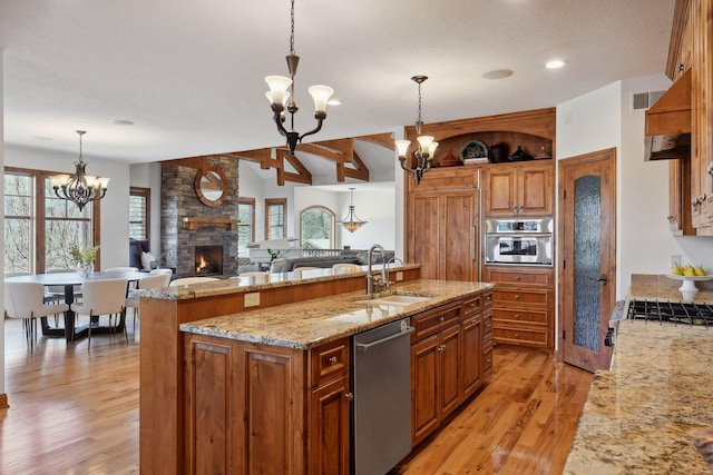 kitchen with pendant lighting, sink, stainless steel appliances, a center island with sink, and an inviting chandelier