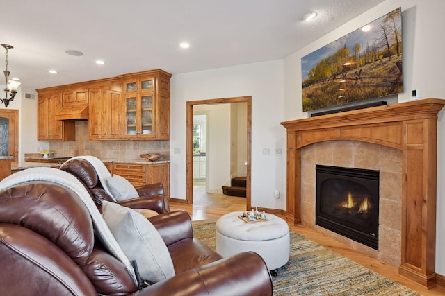 living room with an inviting chandelier, a fireplace, and light wood-type flooring