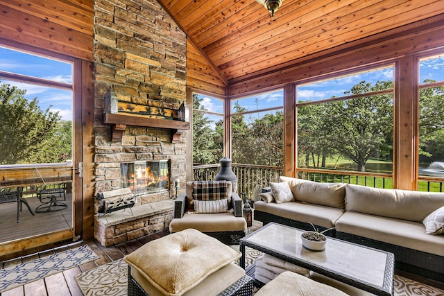 sunroom featuring wood ceiling, a stone fireplace, and vaulted ceiling