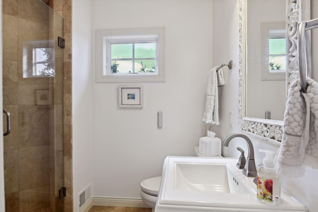 bathroom featuring a wealth of natural light, an enclosed shower, and toilet