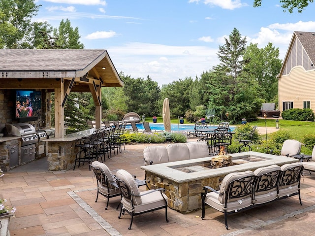 view of patio featuring an outdoor kitchen, grilling area, an outdoor bar, and an outdoor living space with a fire pit