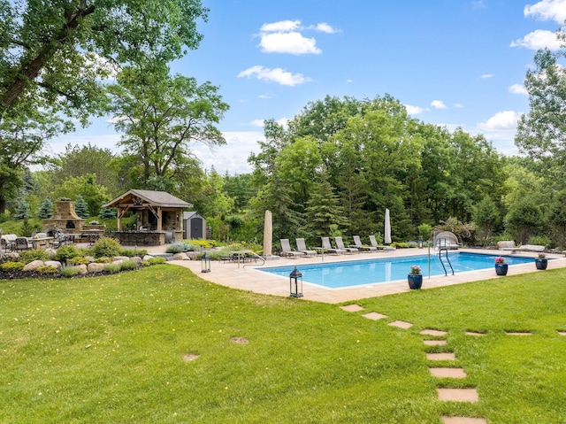 view of pool with a storage shed, a yard, a patio area, and an outdoor stone fireplace