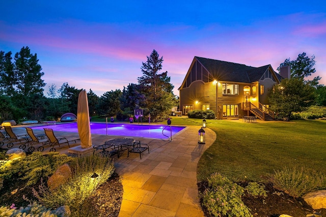 pool at dusk with a yard and a patio