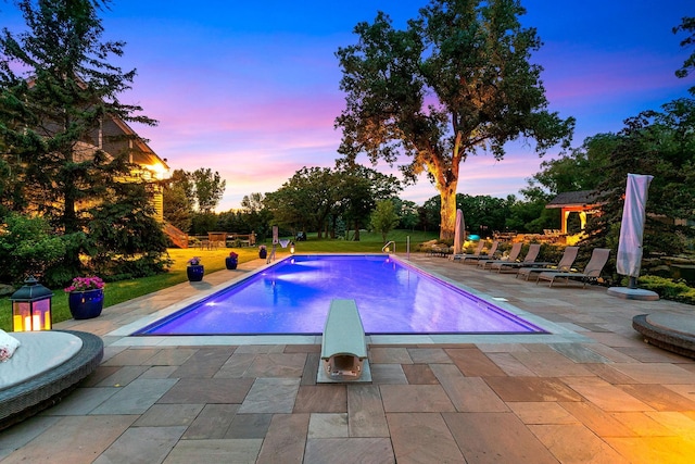 pool at dusk featuring a patio