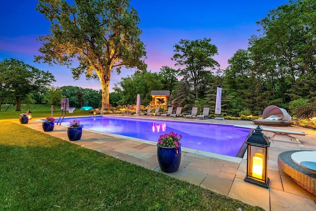 pool at dusk featuring a yard and a patio area