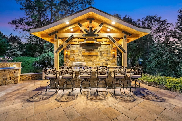 patio terrace at dusk featuring a grill and exterior bar